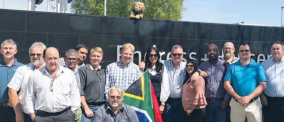 Delegates to Endress+Hauser’s Hannover Messe Training Tour 2018 pose for a photograph. The tour mascot looks on from the wall.